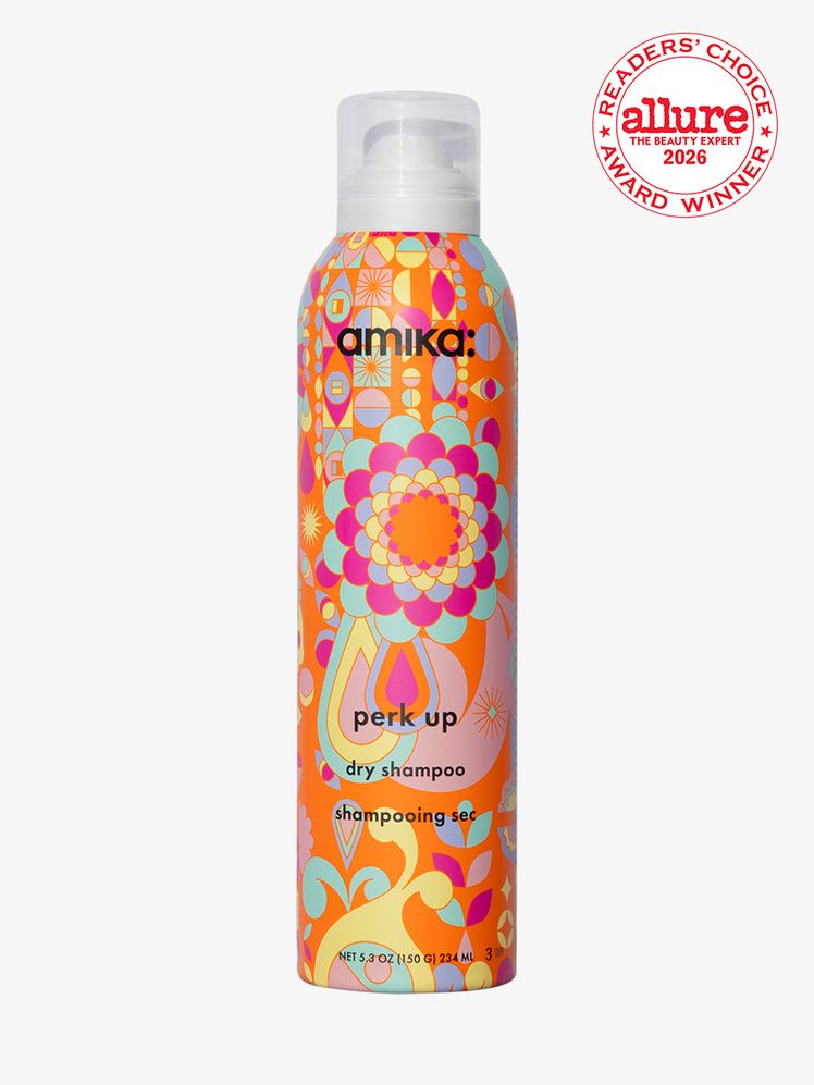Spray bottle of amika Perk Up Dry Shampoo on white background