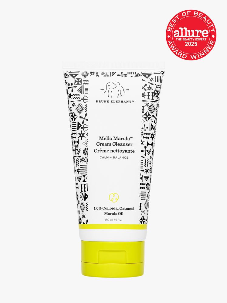 Drunk Elephant Mello Marula Cream Cleanser white bottle with black pattern design and yellow cap on light gray...