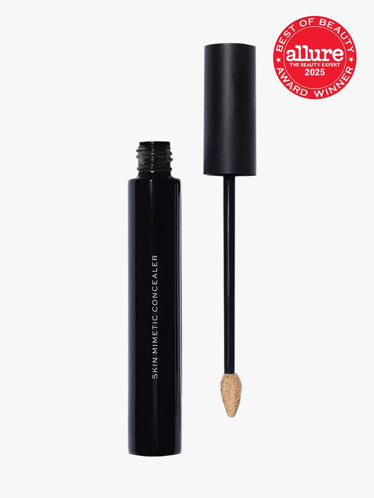 Make Beauty Skin Mimetic Concealer in branded black tube next to doe foot applicator cap on light gray background with...